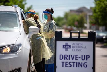 Nurse Kristen Howell, left, and medical lab technician Amanda Hernandez administer a test for the new coronavirus at the Austin Regional Clinic drive-thru testing site in Kyle.