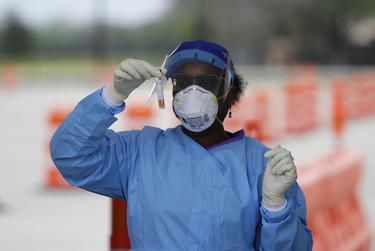 Harris County Health Department nurse Harriet Lewis administers a test at a Harris Co. testing site located at Stallworth Stadium in Baytown last month.