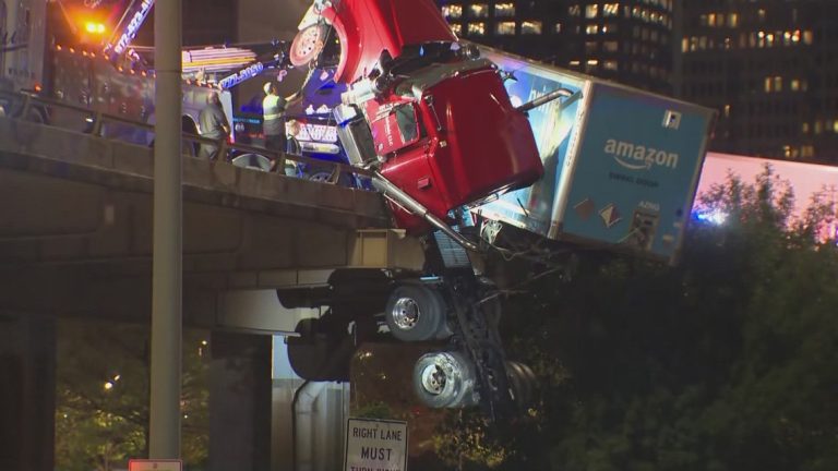 An Amazon 18-wheeler dangles off a bridge in downtown Dallas